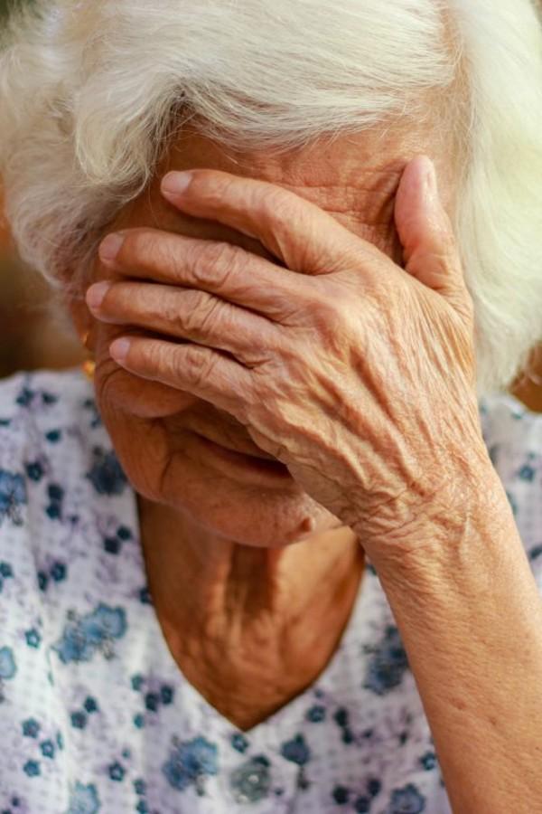 Old woman crying covering her face