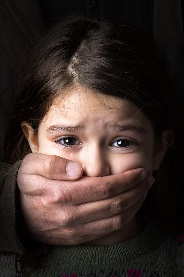 A child with the mouth covered by adult hands